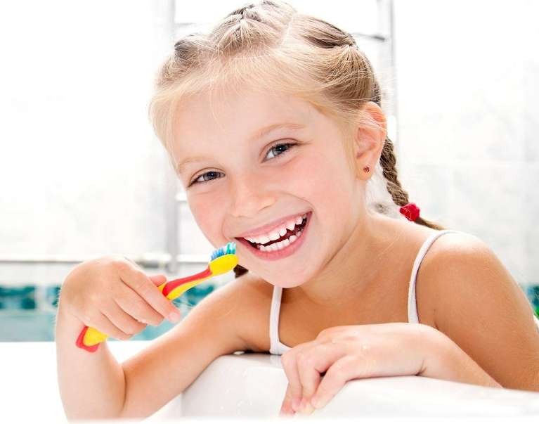 A smiling girl brushing her teeth
