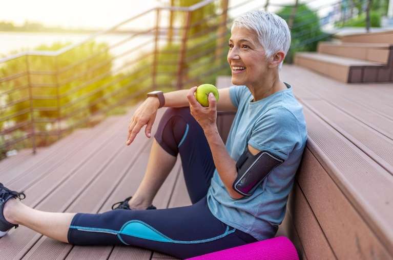 An woman eating an apple after her morning run
