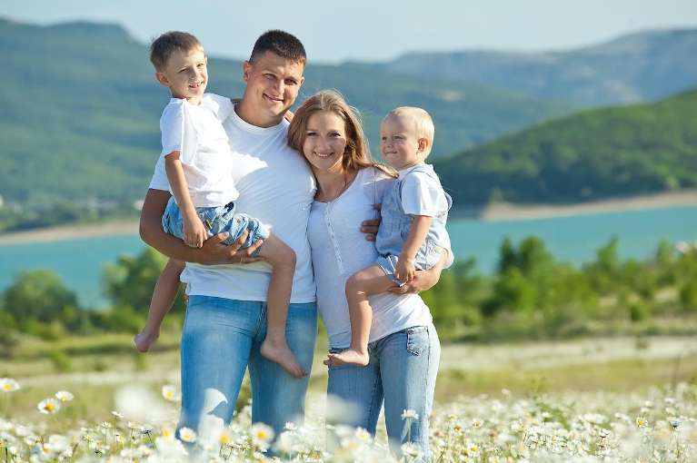 A smiling family posing by the lake
