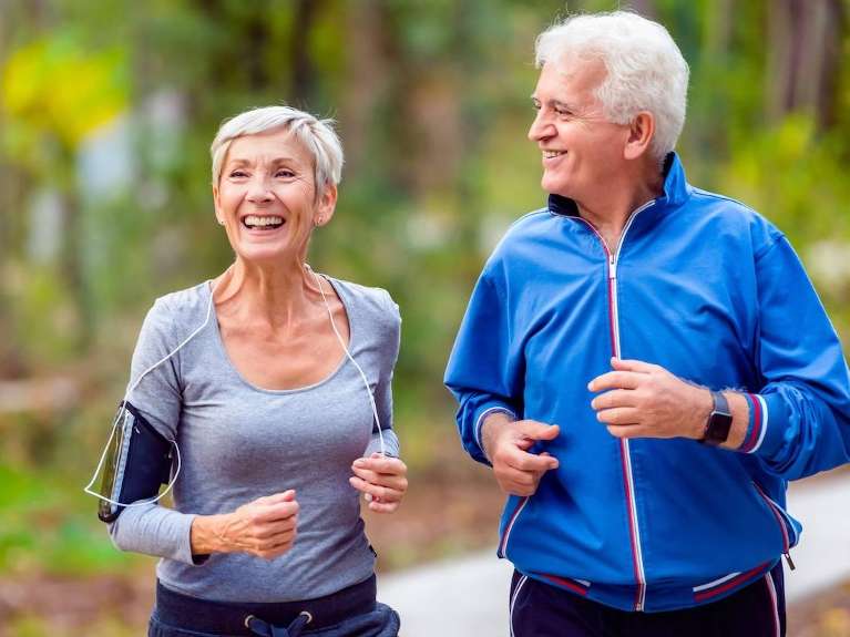A happy older couple jogging in the park