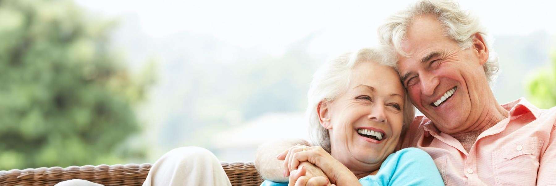 A laughing older couple sitting on a chair