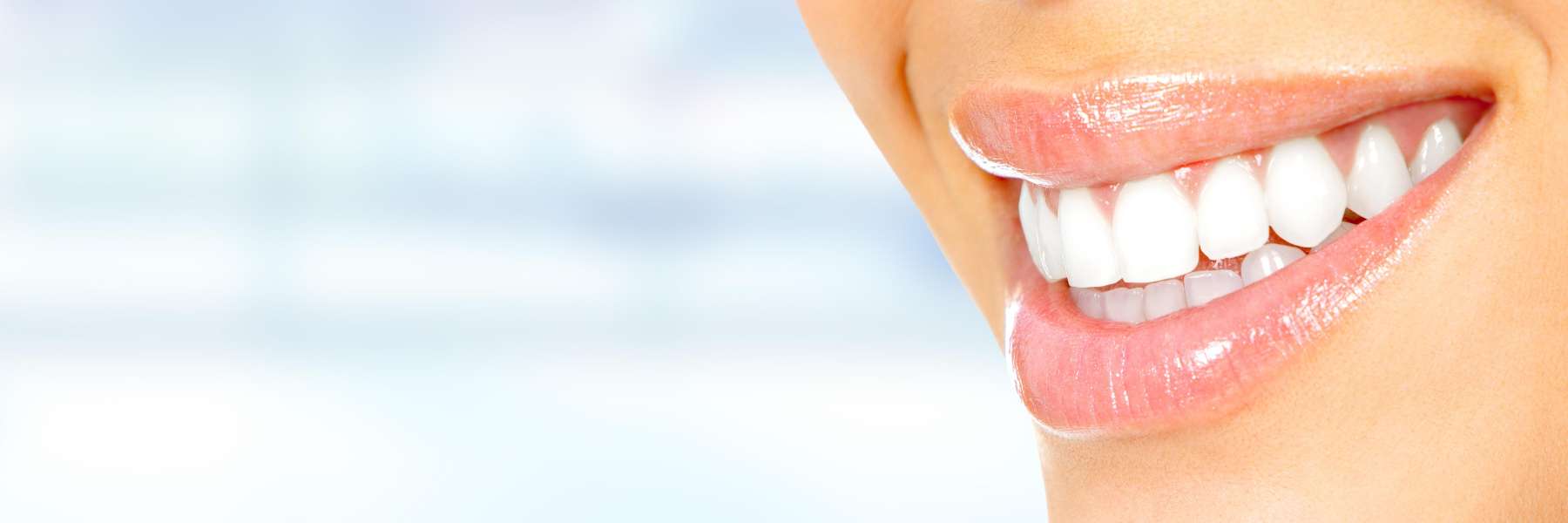 A close-up of a woman's smile shows healthy white teeth and gums, radiating confidence